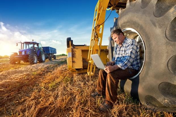 Portrait eines Landwirts, der sein Notebook während der Arbeit auf dem Feld verwendet